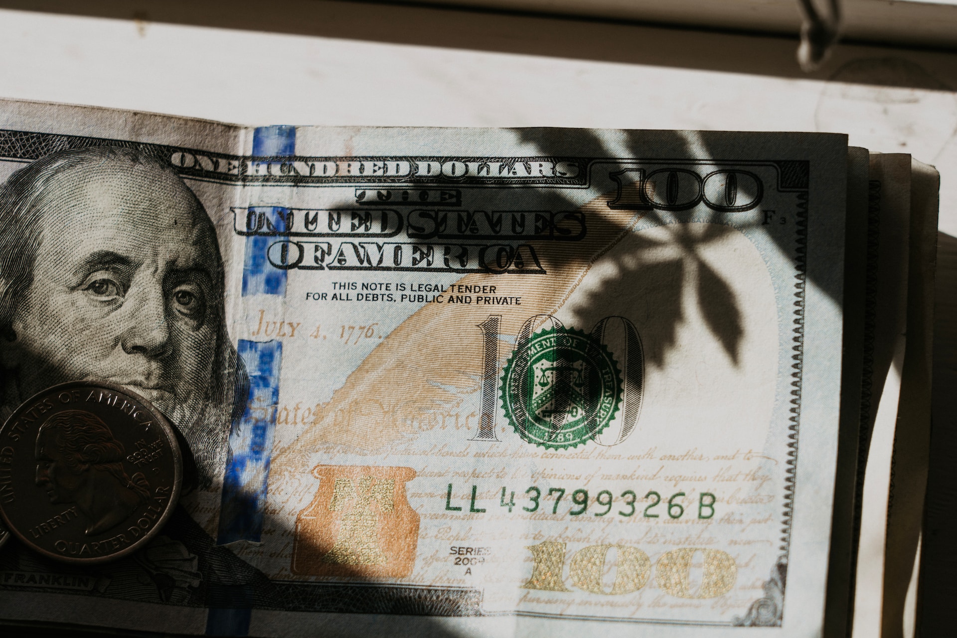 a dollar bill with a shadow of a cannabis leaf